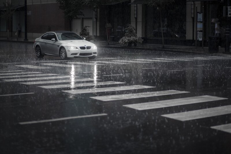 white car in rain at crosswalk