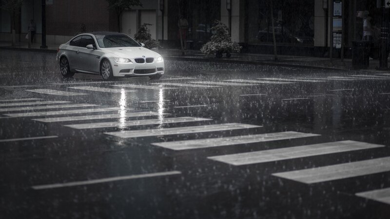 White car in rain on city street