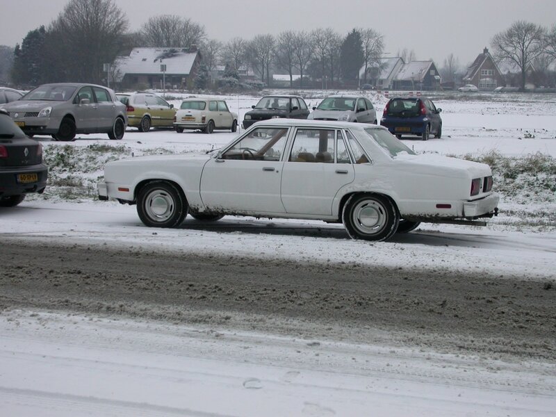 White car in snowy parking lot