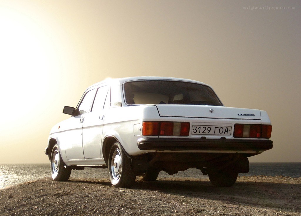 White car on a beach at sunset