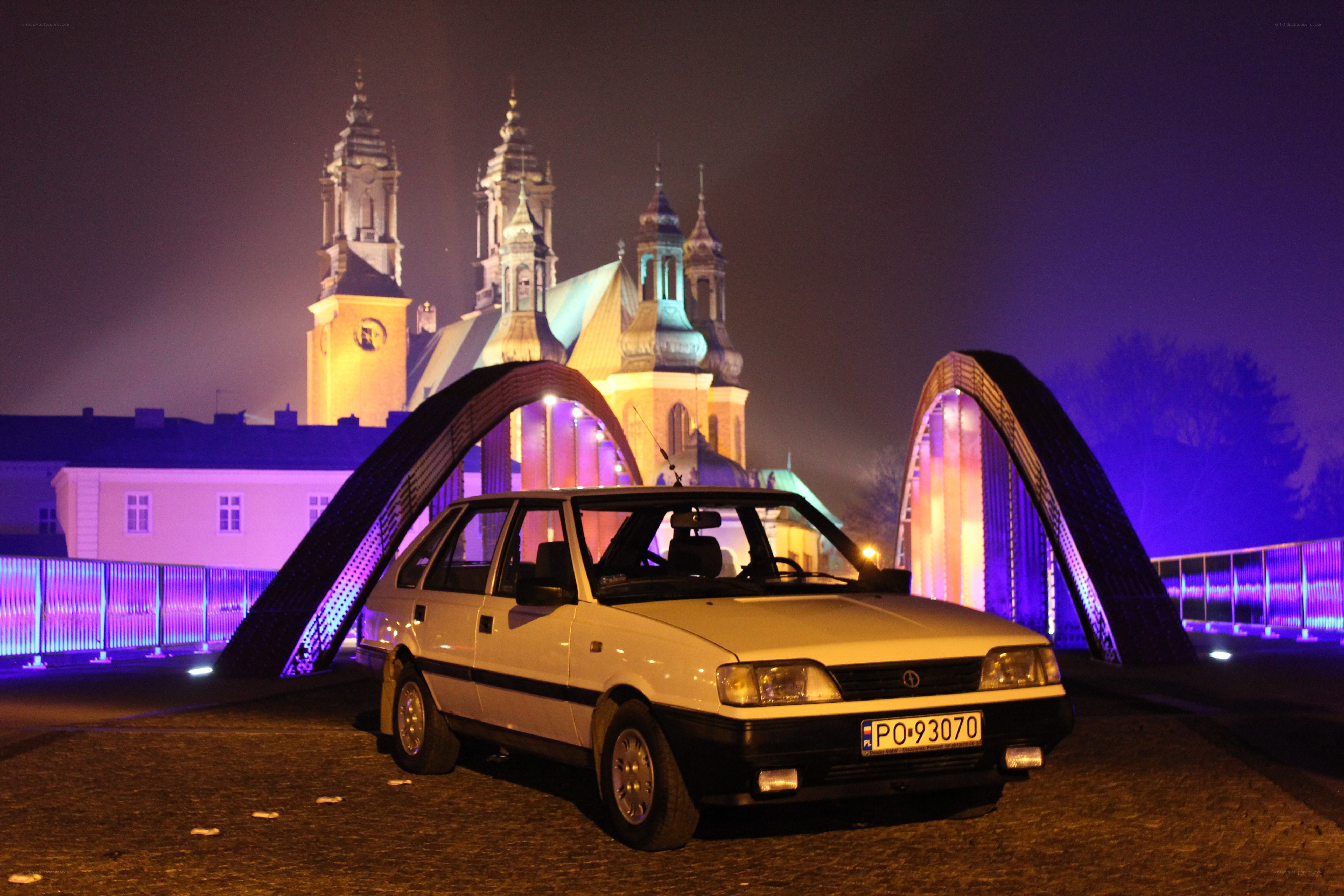 White car on a lit bridge