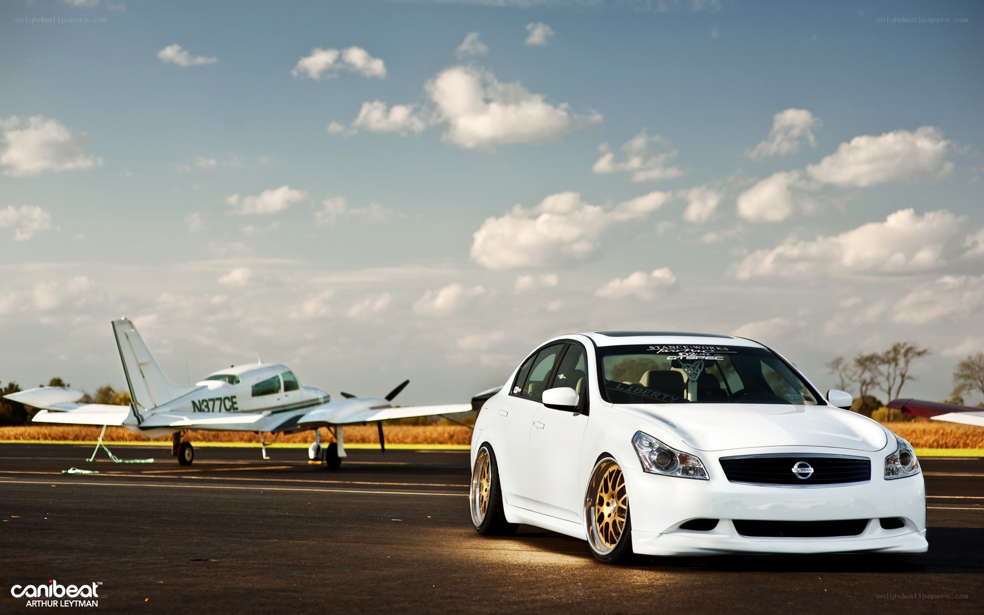 White car on airfield with plane