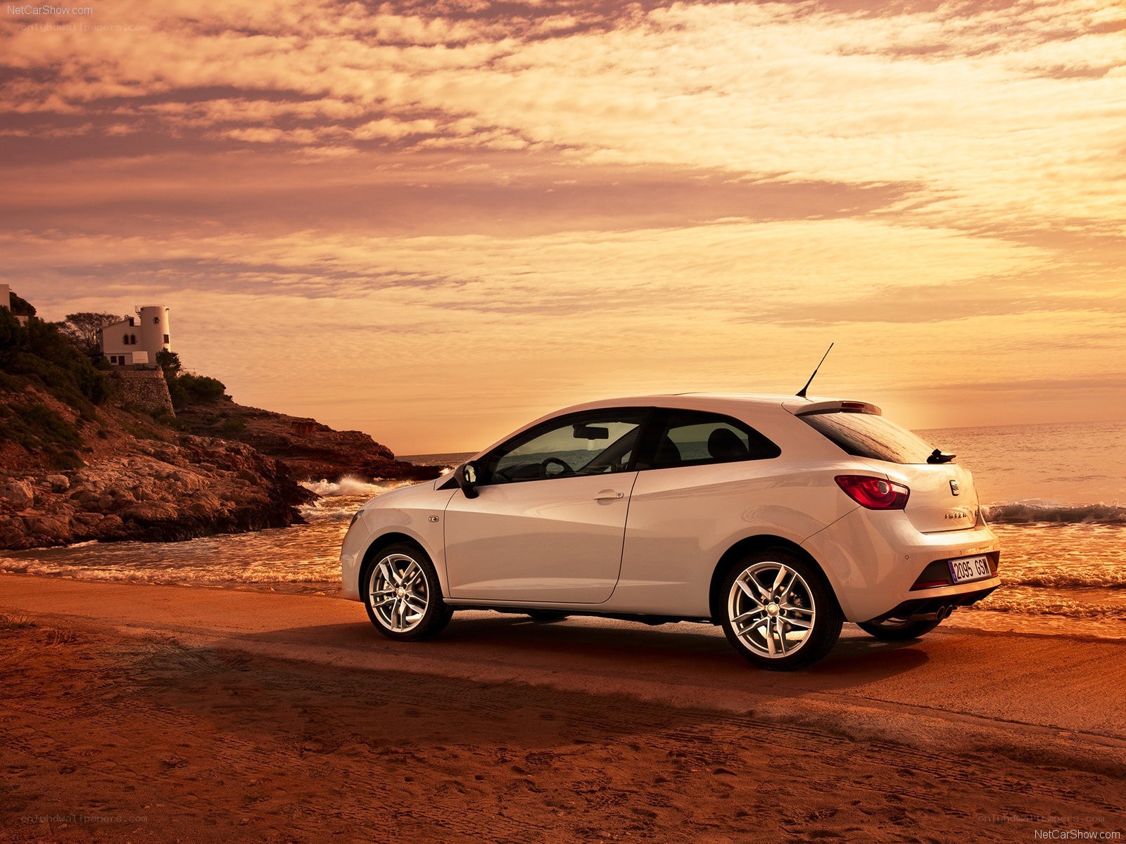 White car on beach at sunset