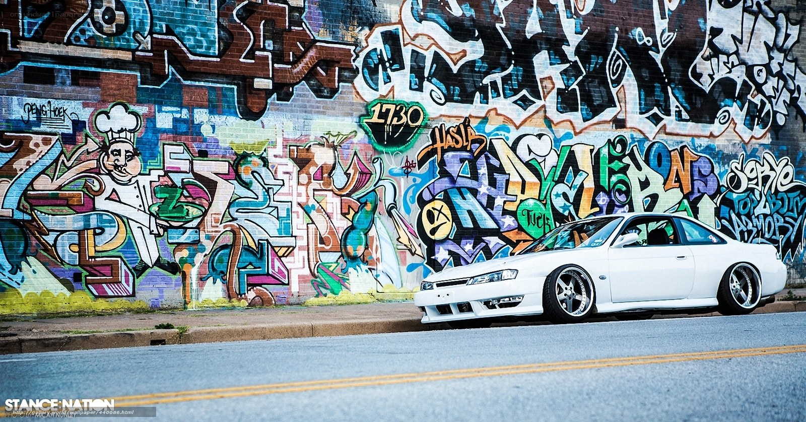 White car parked by graffiti wall