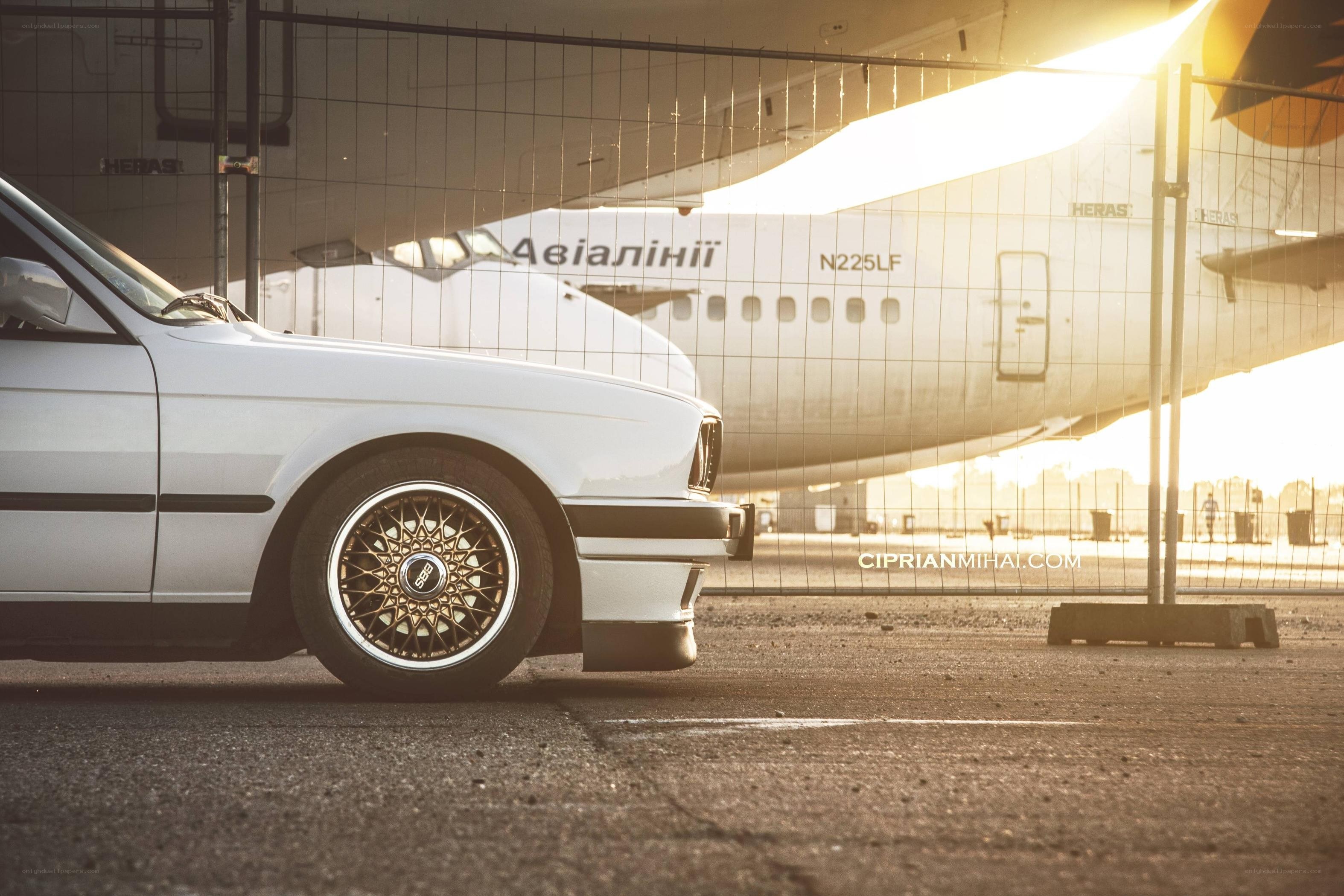White car with airplane in background