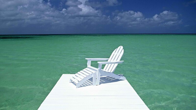 White chair on dock by ocean