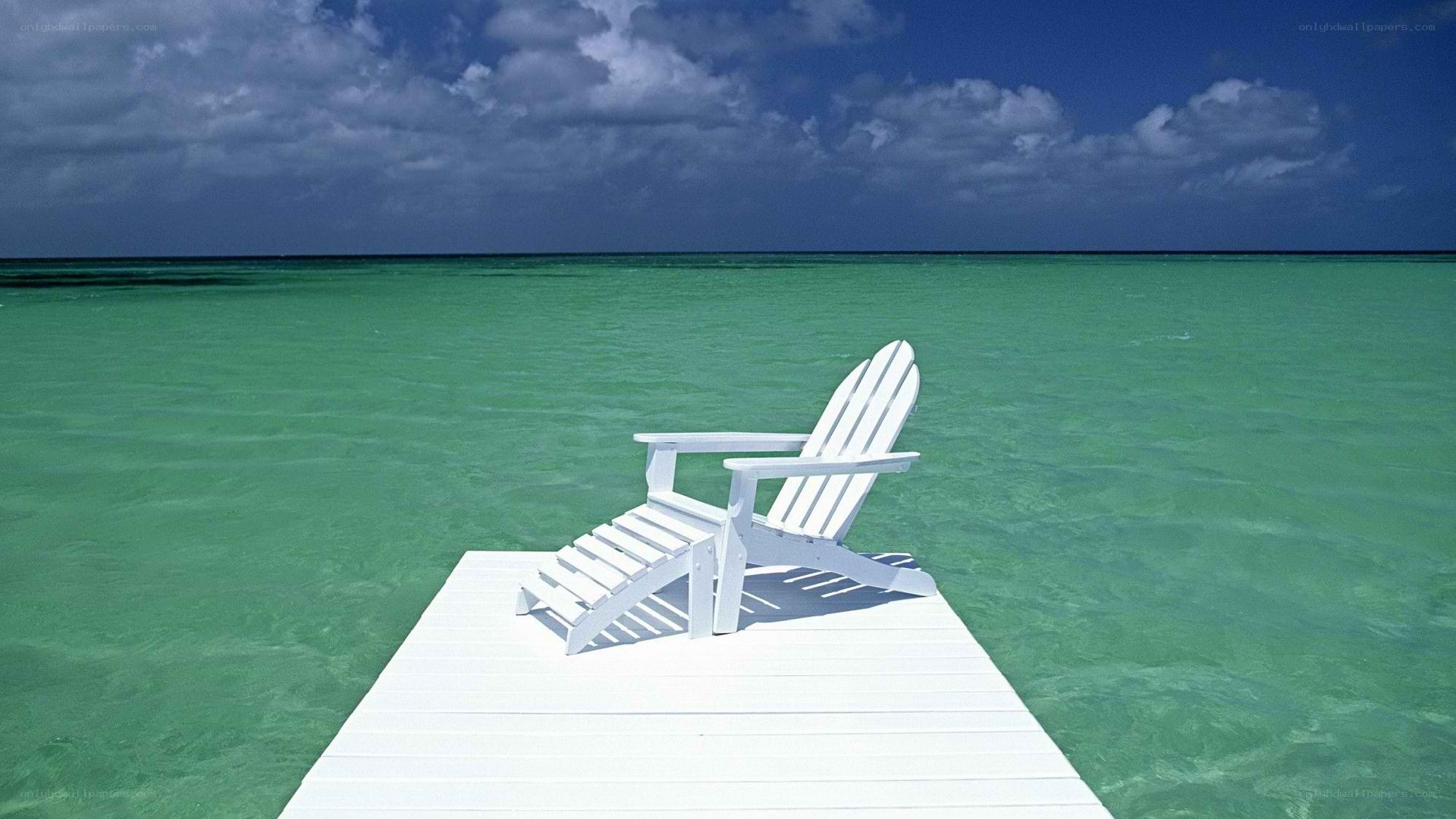 White chair on dock by ocean