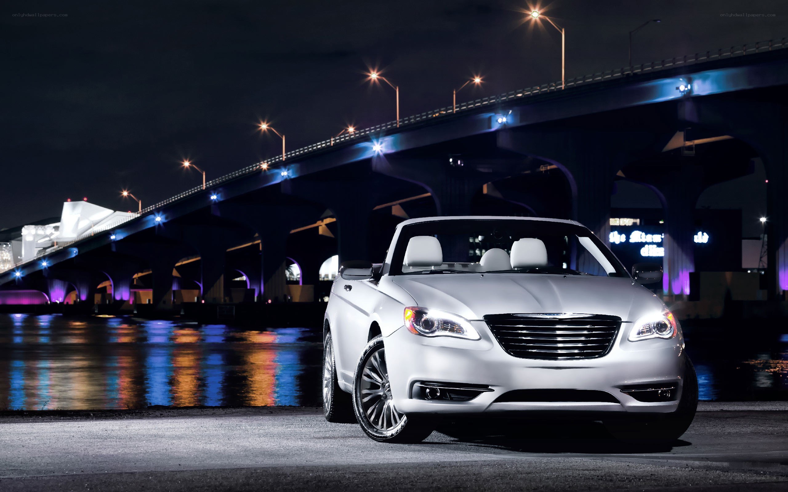White convertible by a bridge at night