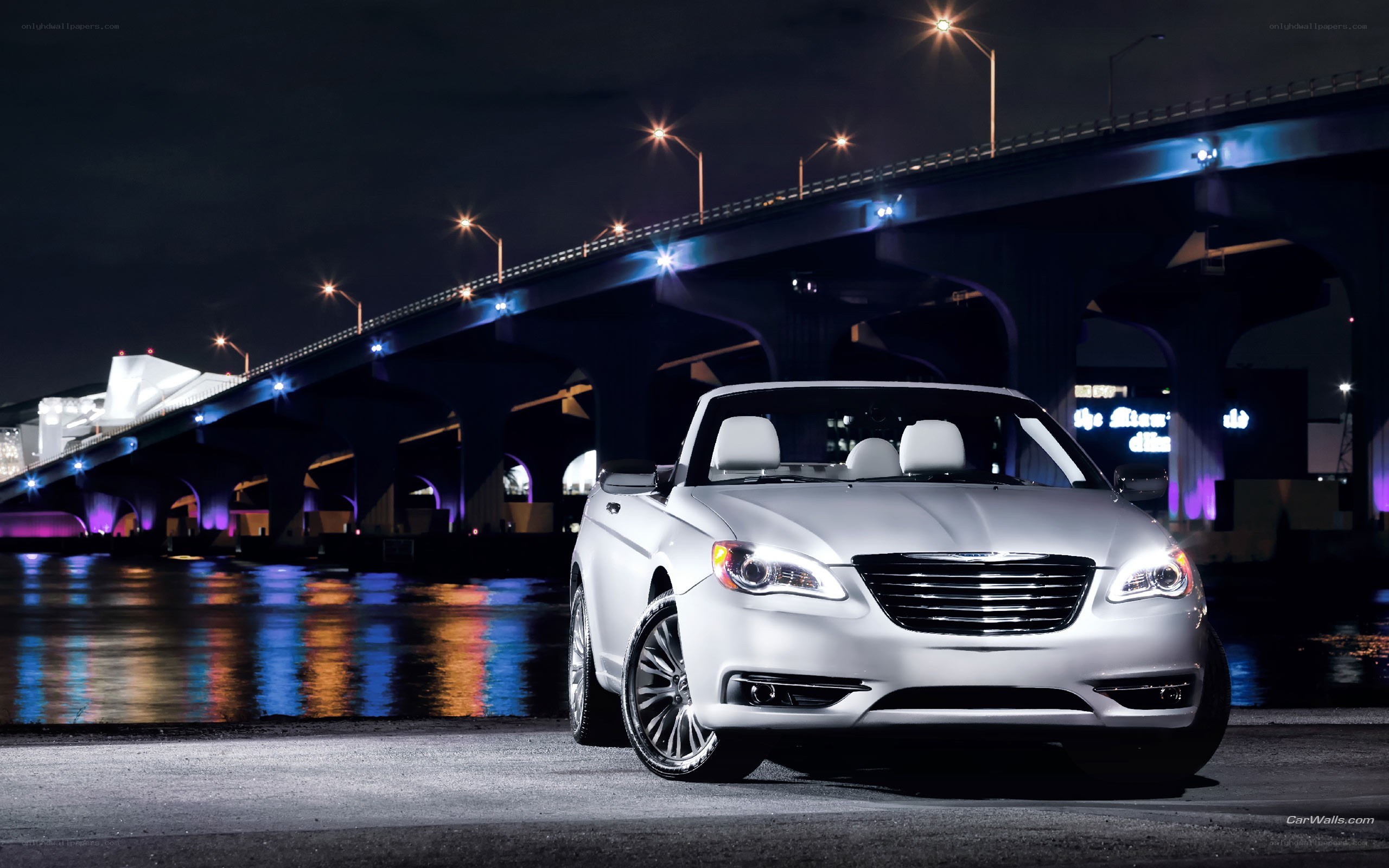 White convertible by a bridge at night