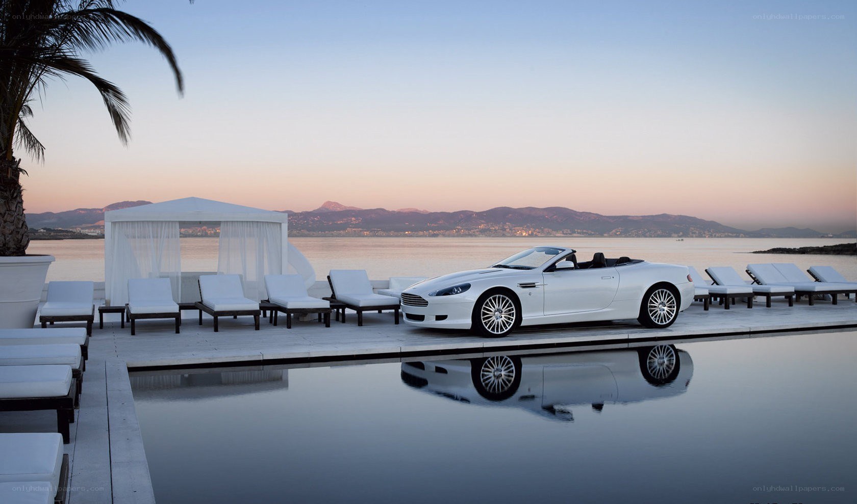 White convertible by pool at sunset