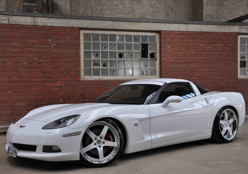 White Corvette in front of brick wall