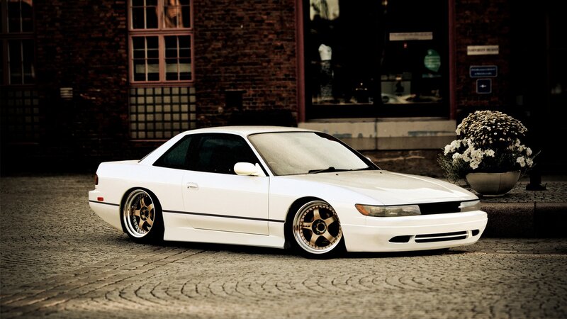 White Coupe Car — Dramatic, Photograph, Brick Building