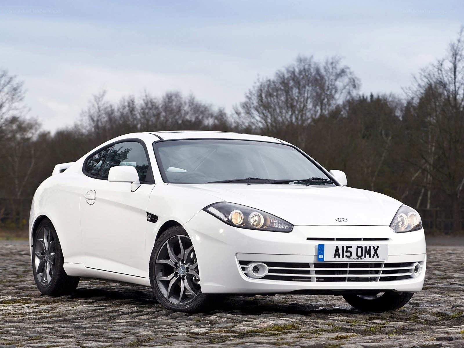 white coupe on cobblestones
