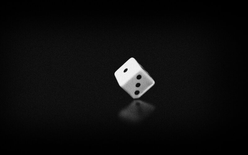 White Die on Black Surface — Dramatic