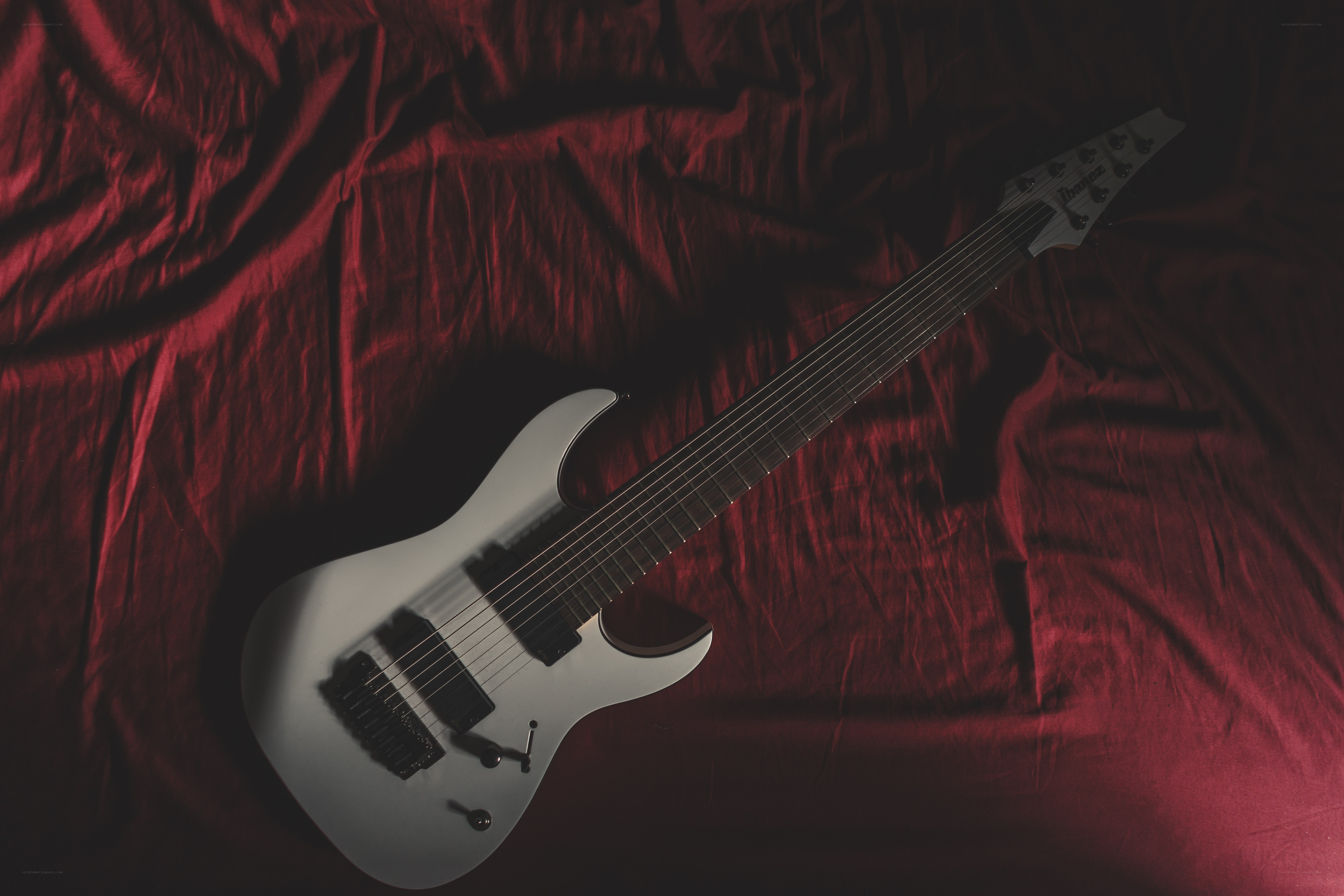 white electric guitar on red fabric