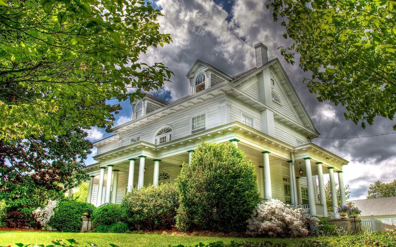white house with porch and greenery