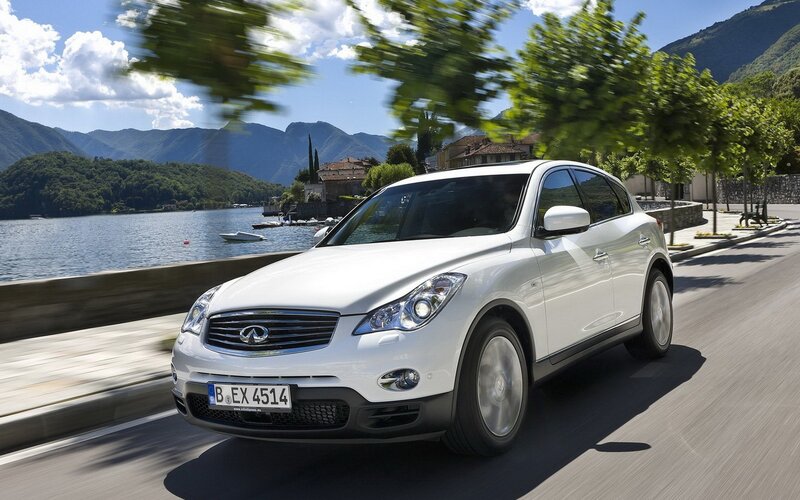 White Infiniti driving by a lake