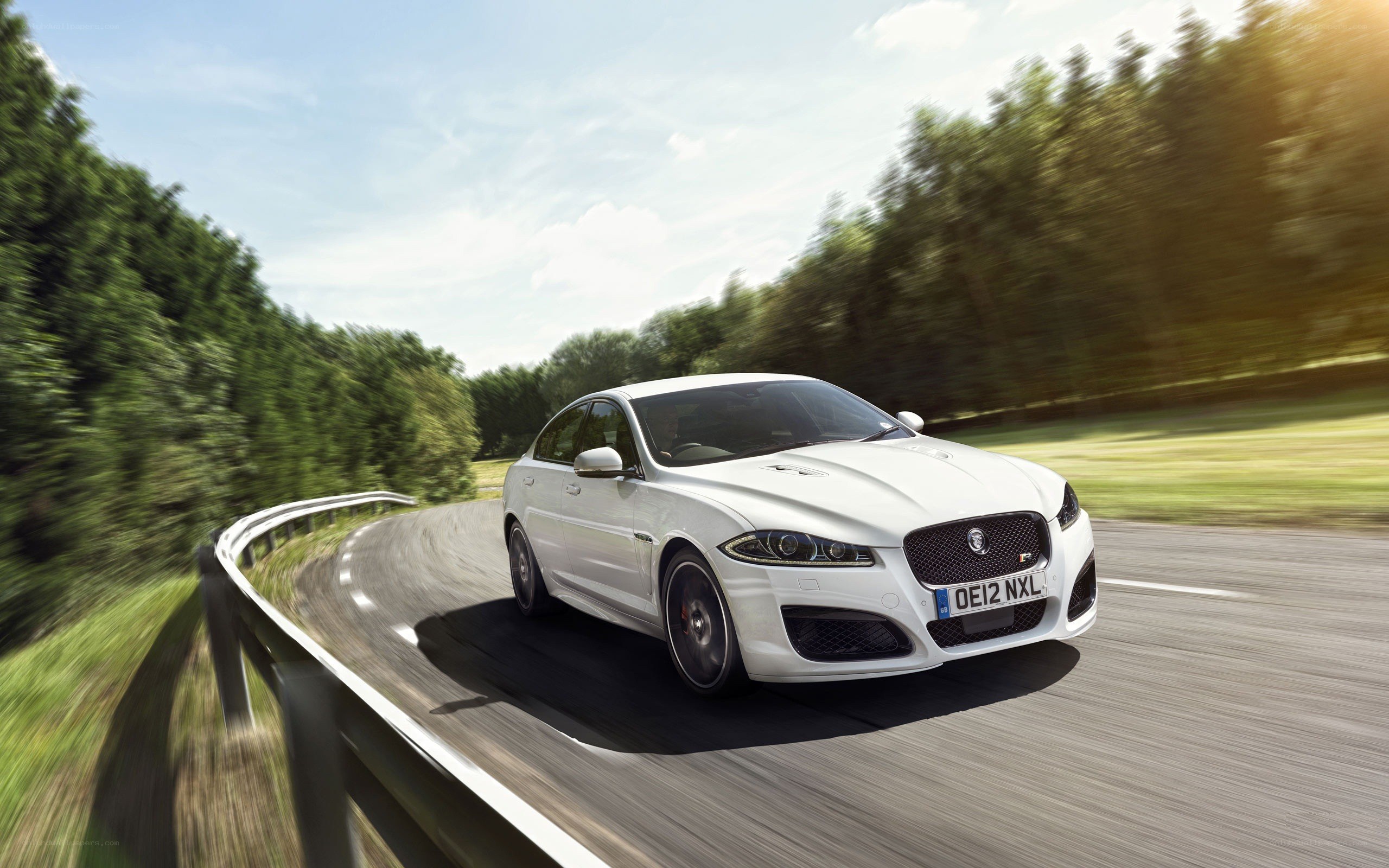 White Jaguar driving on a road