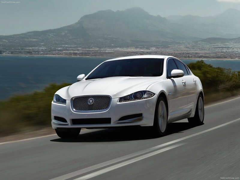 white jaguar driving on coastal road