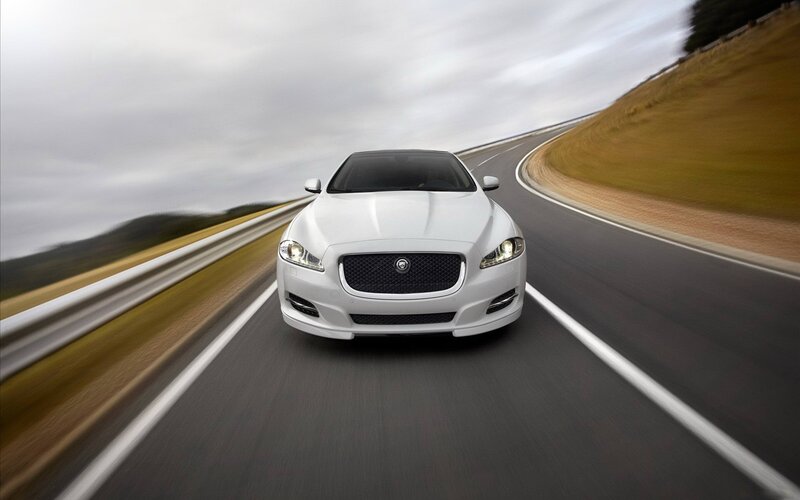 white jaguar driving on road