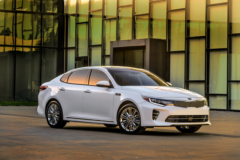 White Kia sedan in front of building