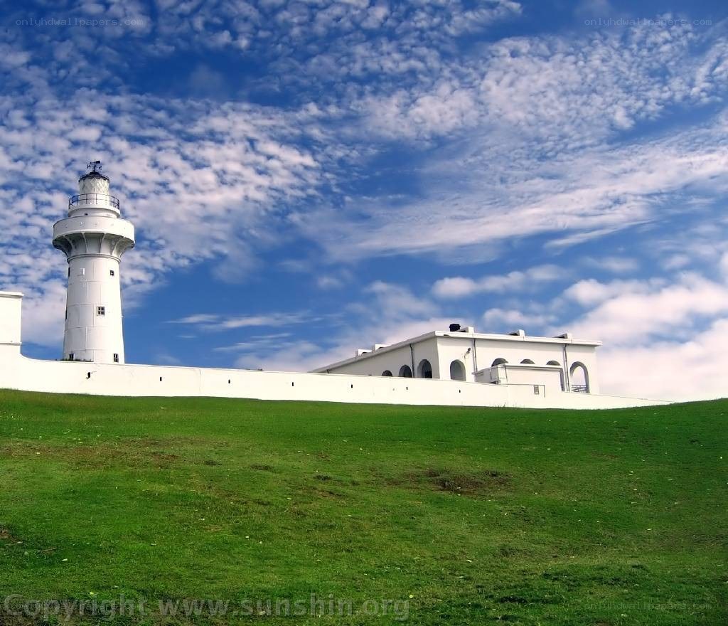 White lighthouse on a green hill