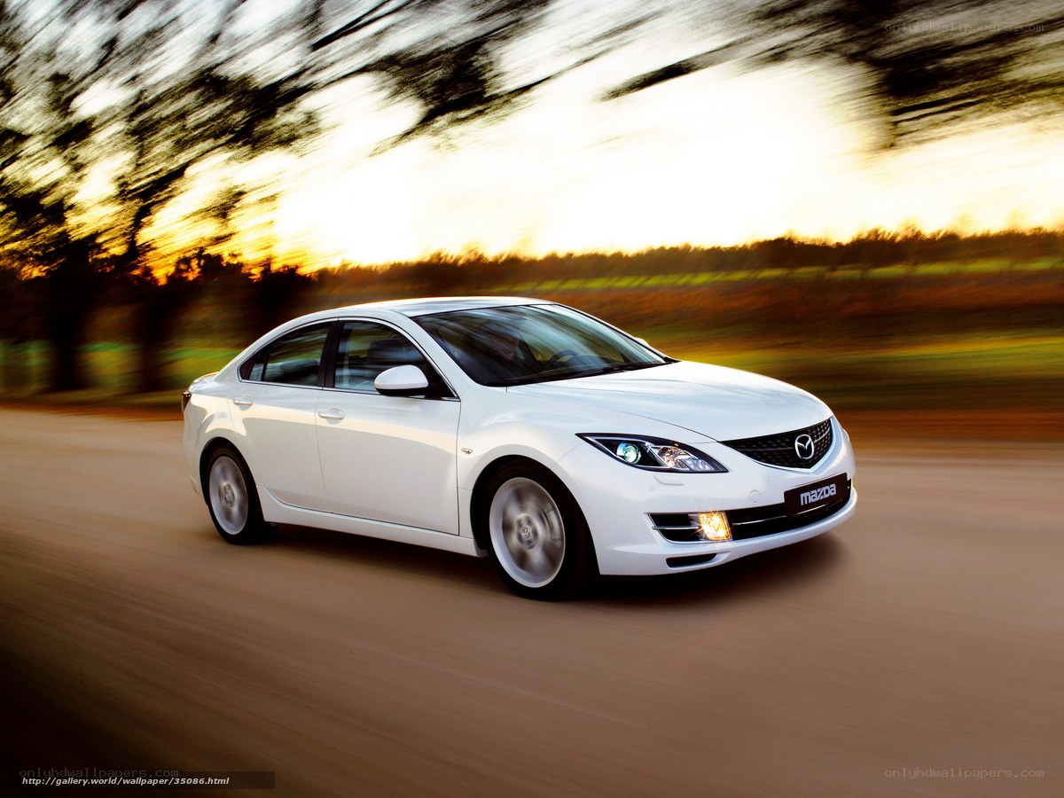 White Mazda driving on a road