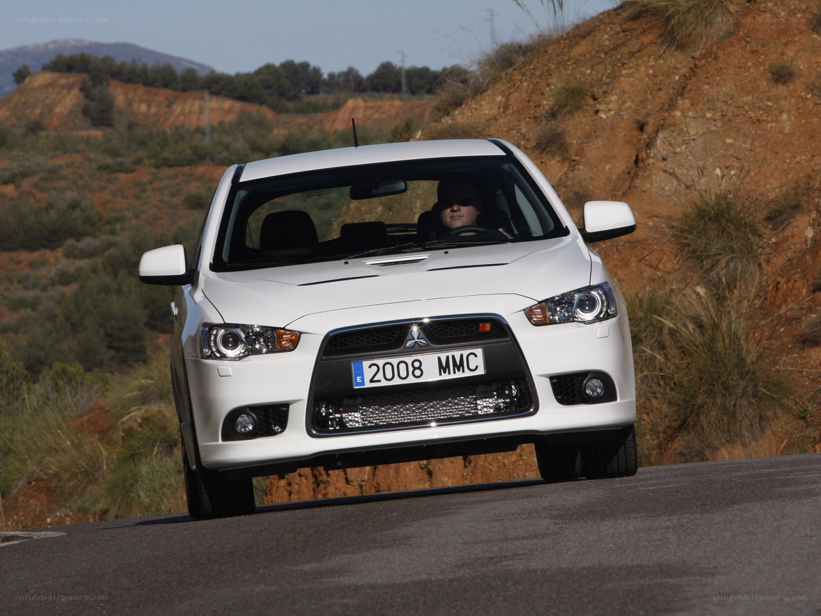 white mitsubishi lancer driving on road