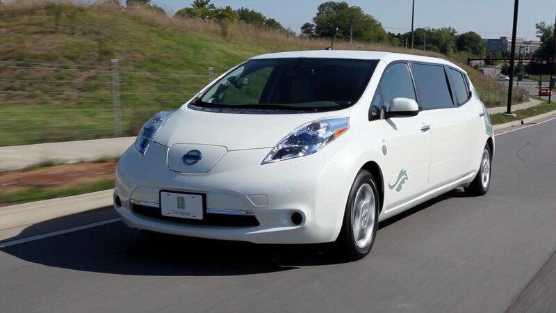 white nissan leaf driving on road