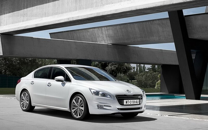 White Peugeot sedan under concrete structure