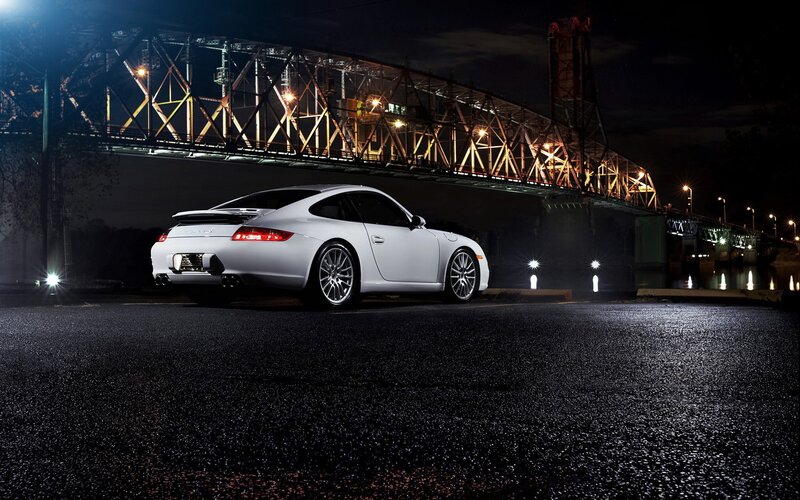 White Porsche at night under a bridge