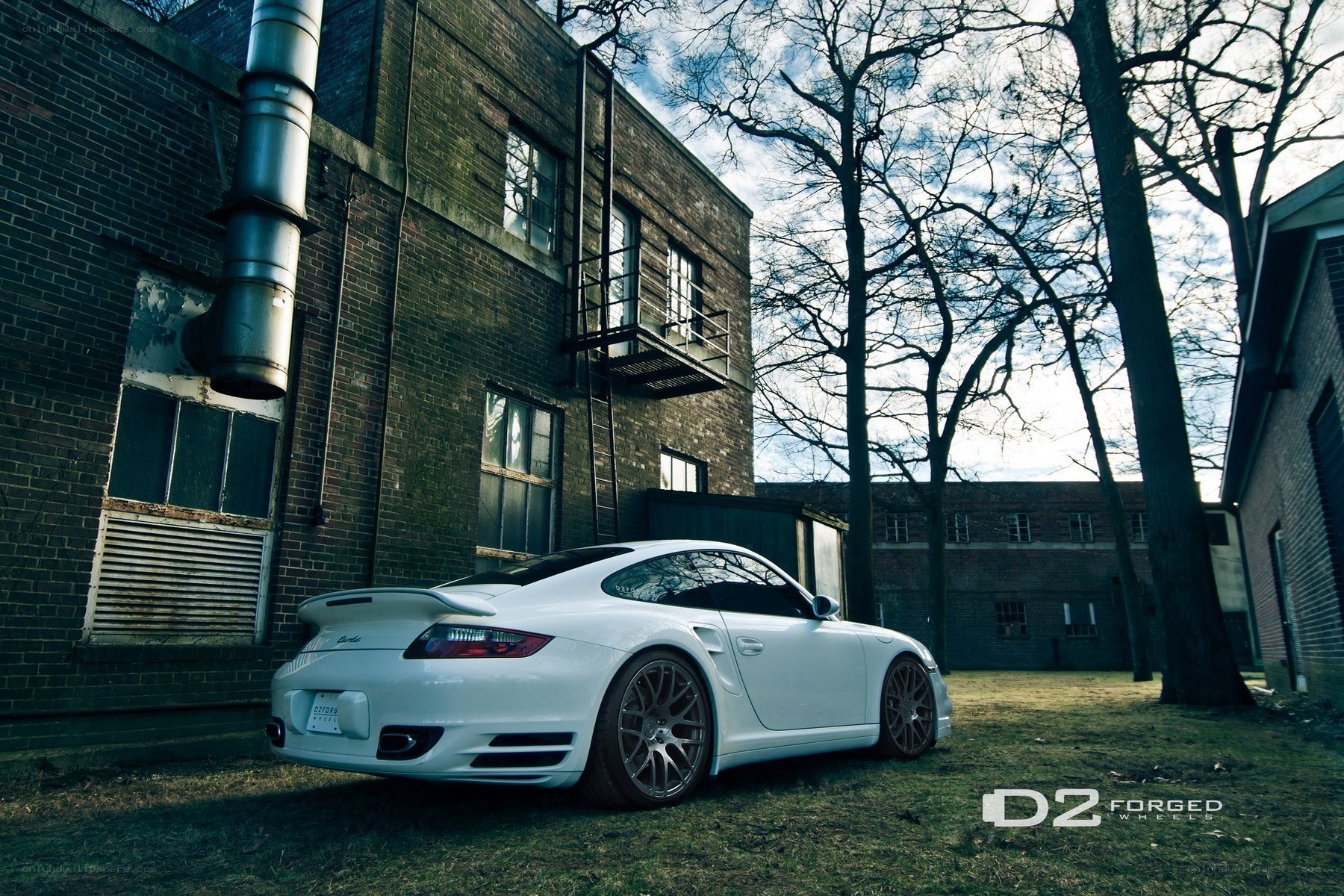 White Porsche parked by brick building