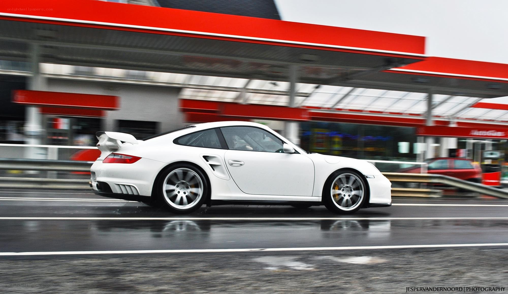 White Porsche speeding past gas station