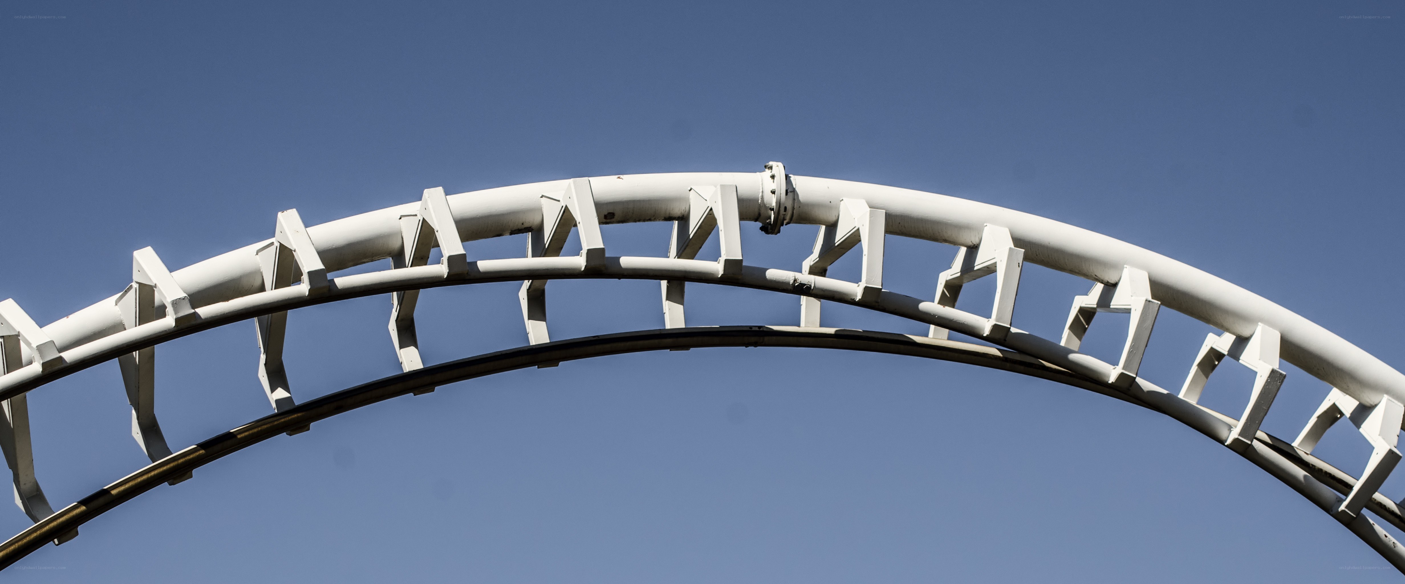 White roller coaster track against blue sky