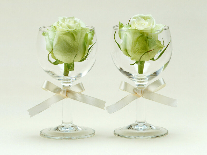 white roses in wine glasses