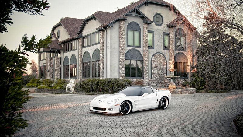 White sports car in front of mansion