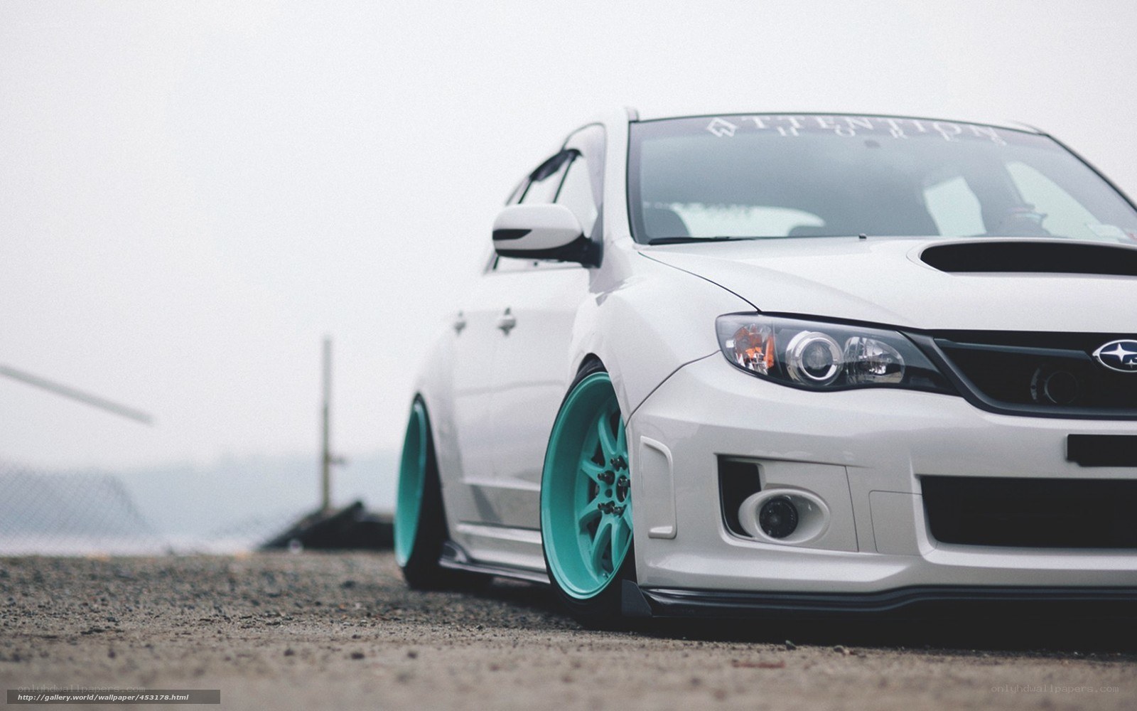 white subaru with teal wheels