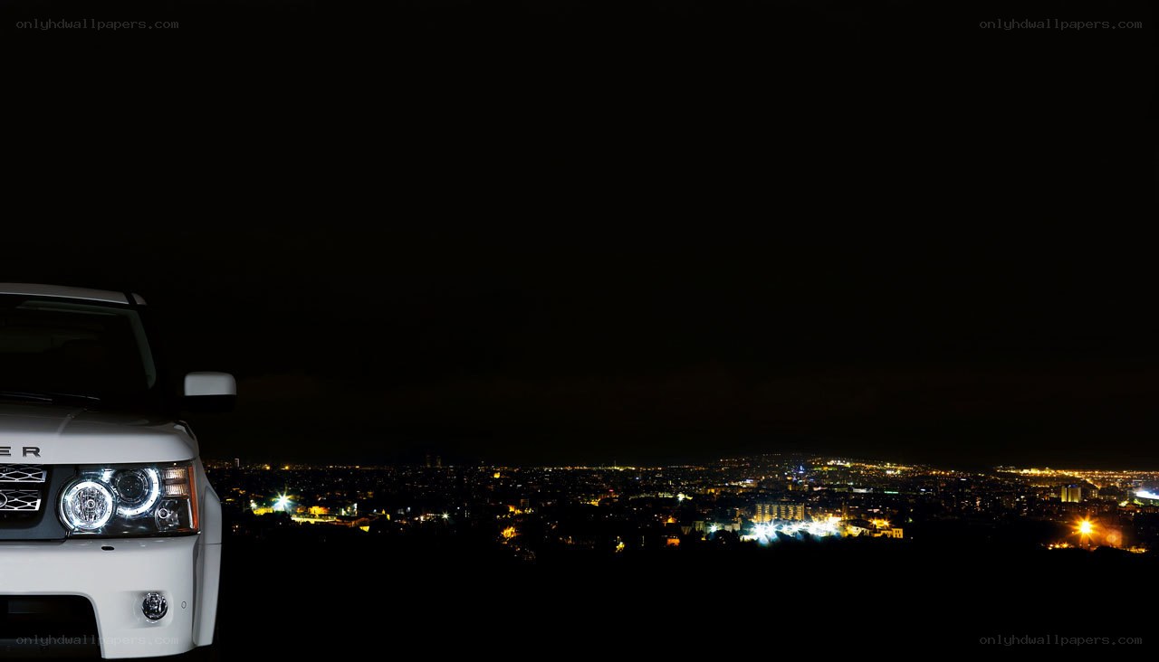 White SUV at night overlooking city