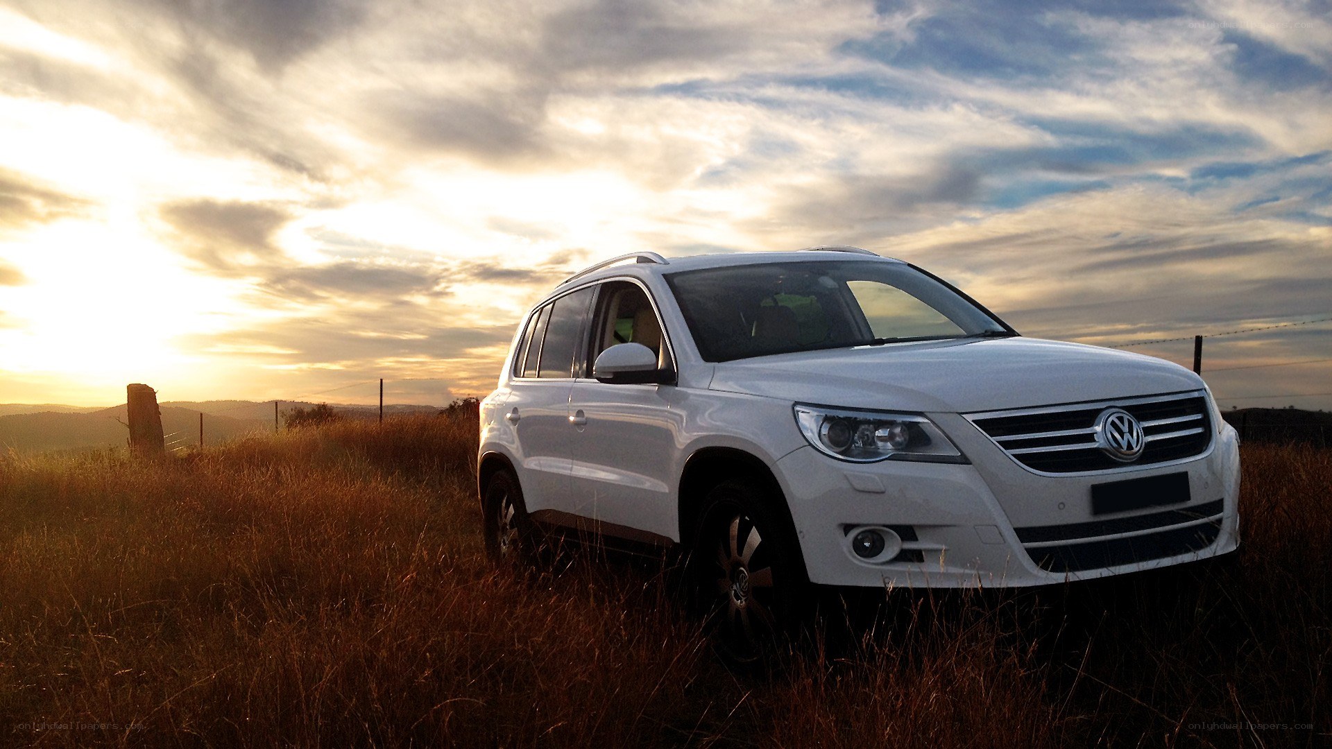 White SUV in a field at sunset