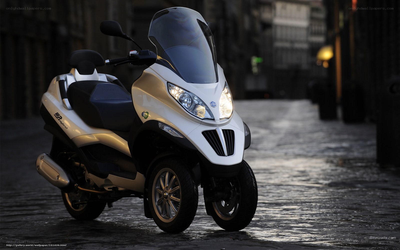 White three-wheeled scooter on cobblestone