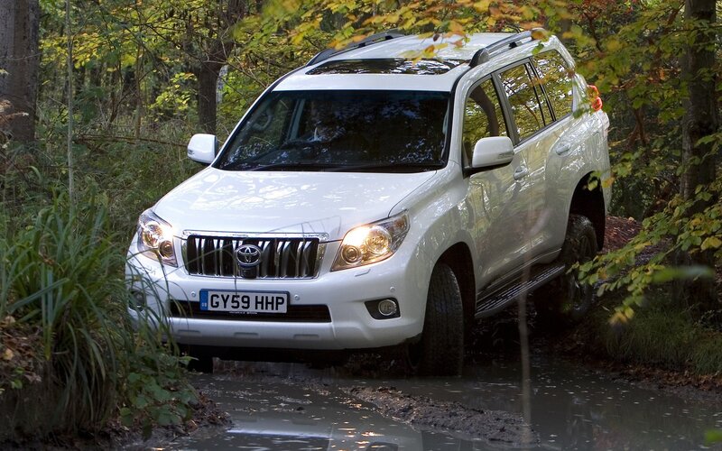 White Toyota Land Cruiser driving through mud