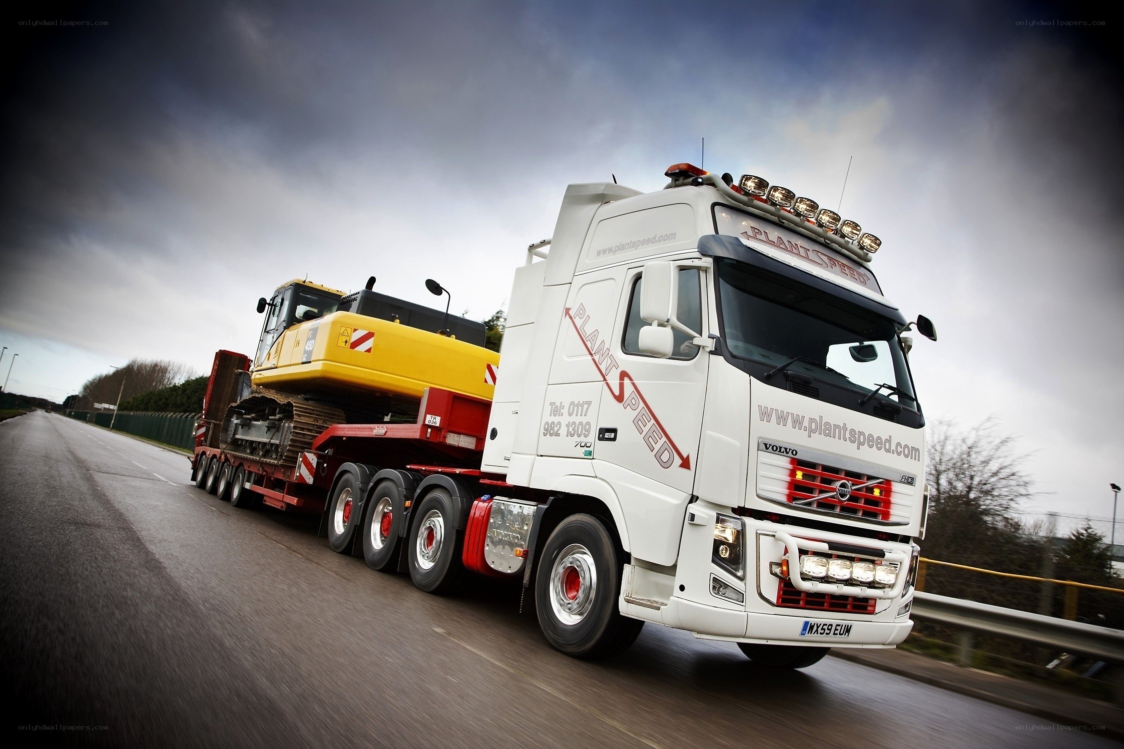 White truck carrying excavator