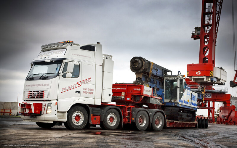 White truck carrying heavy machinery