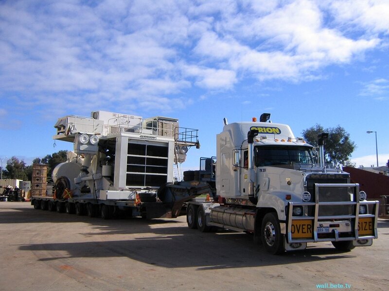 White truck hauling heavy machinery