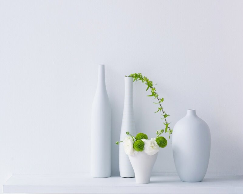 white vases with greenery