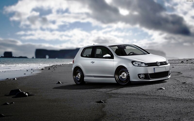 White Volkswagen on a black sand beach