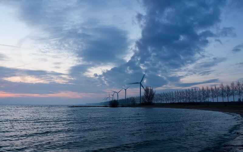 Wind turbines at dusk by the water