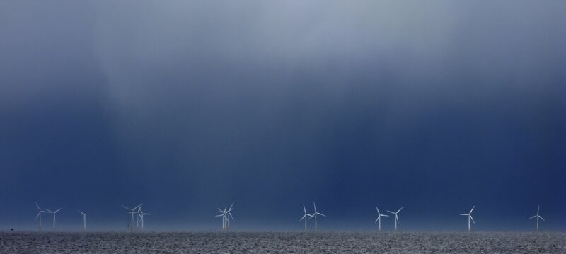 Wind turbines at sea under stormy sky