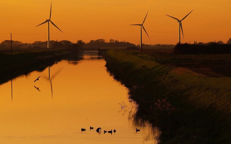 Wind turbines at sunset by a canal