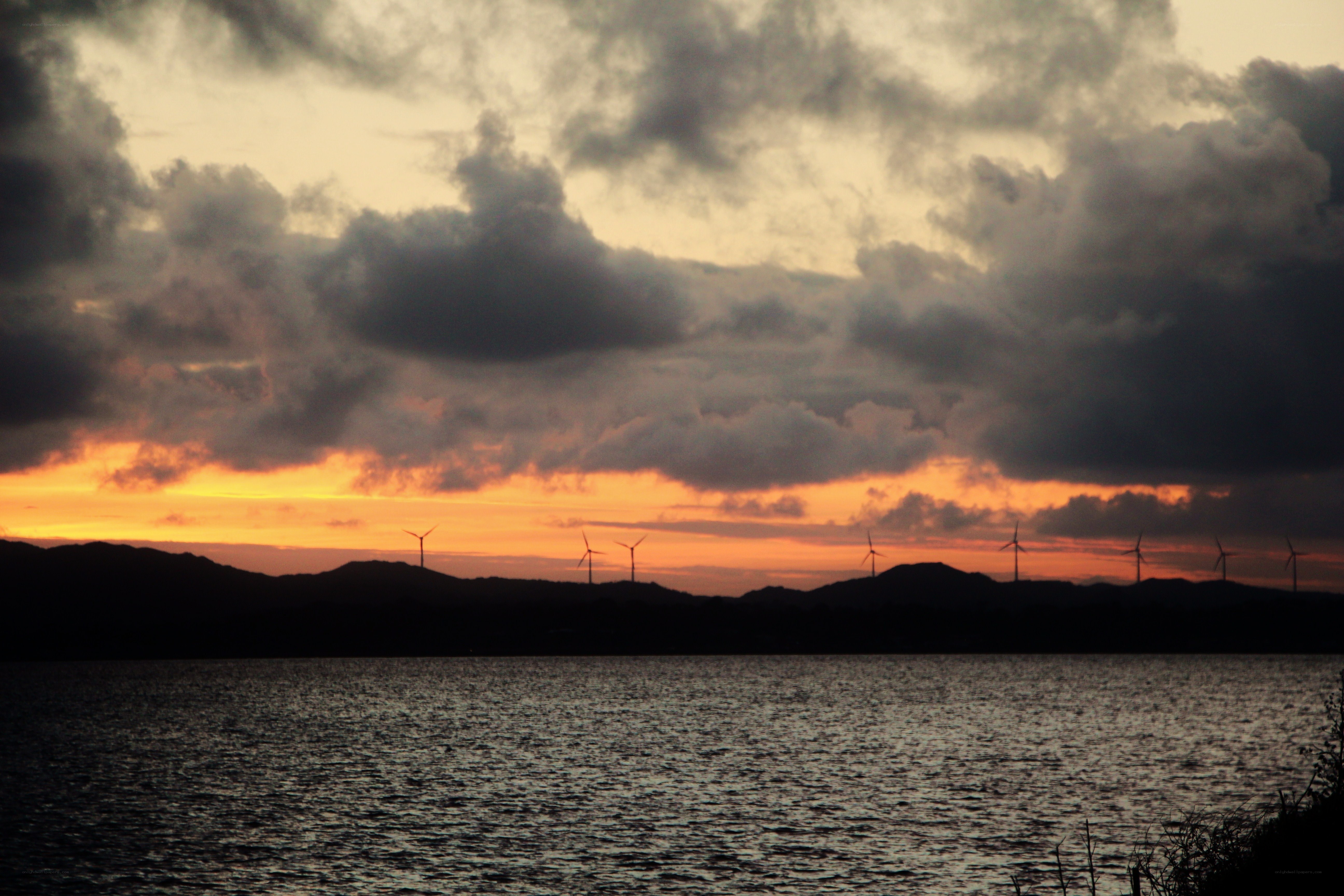 Wind turbines at sunset over water